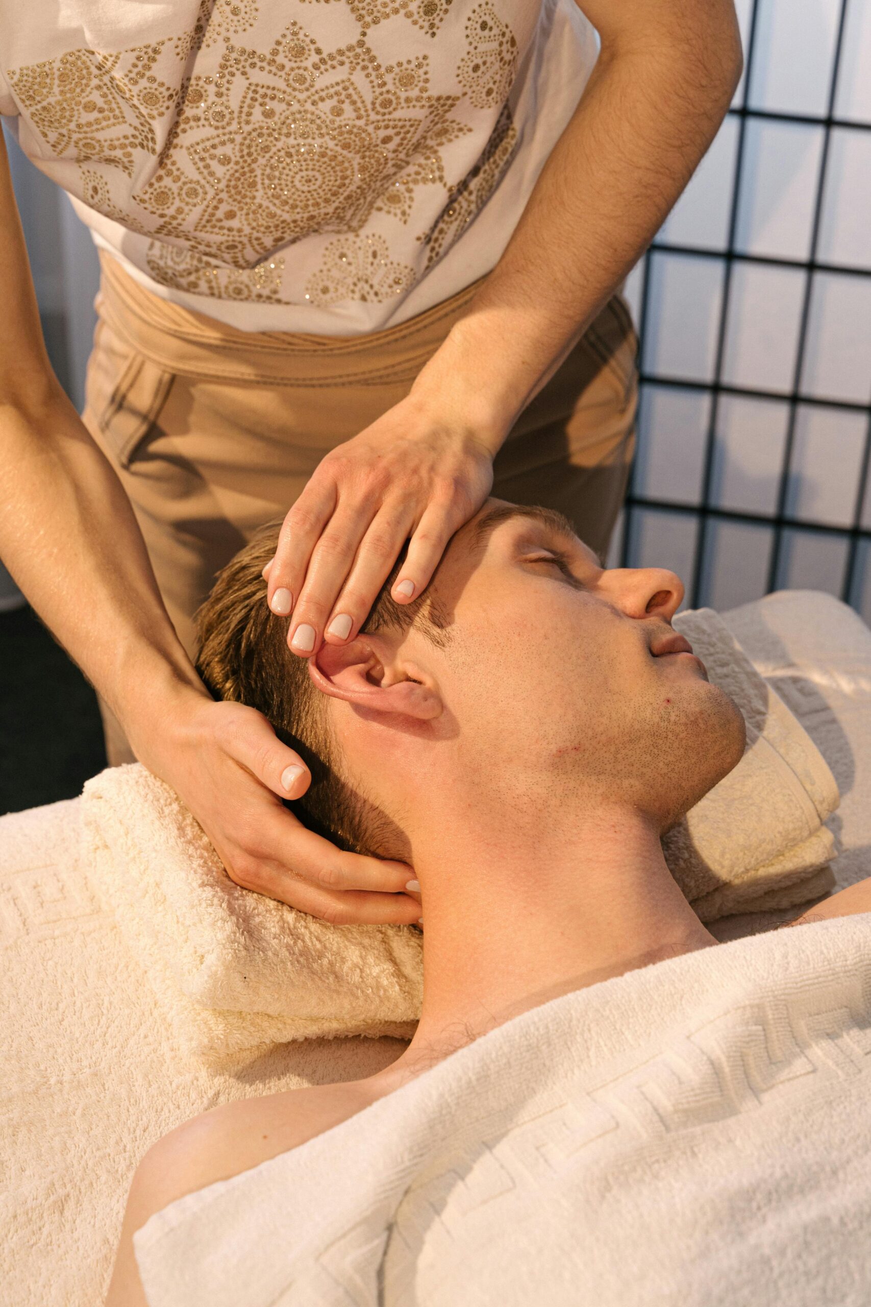 Close-up of a man receiving a relaxing head massage in a tranquil spa environment.